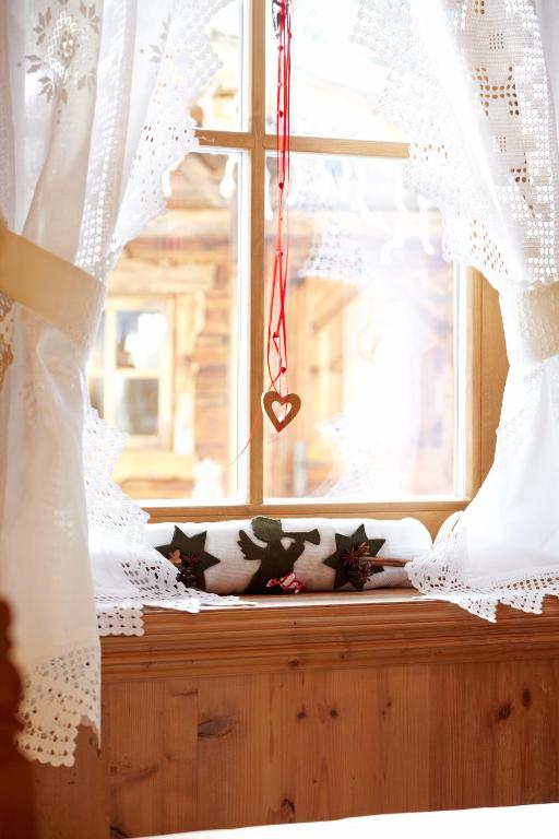 a window with white curtains and a valance at Hotel Genziana in Selva di Val Gardena