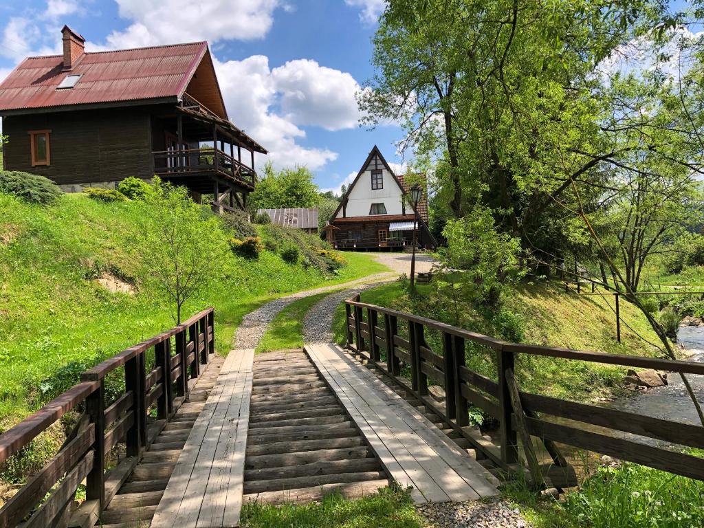ein Haus auf einem Hügel mit einer Holzbrücke in der Unterkunft Sadyba Vanda in Oryavchyk