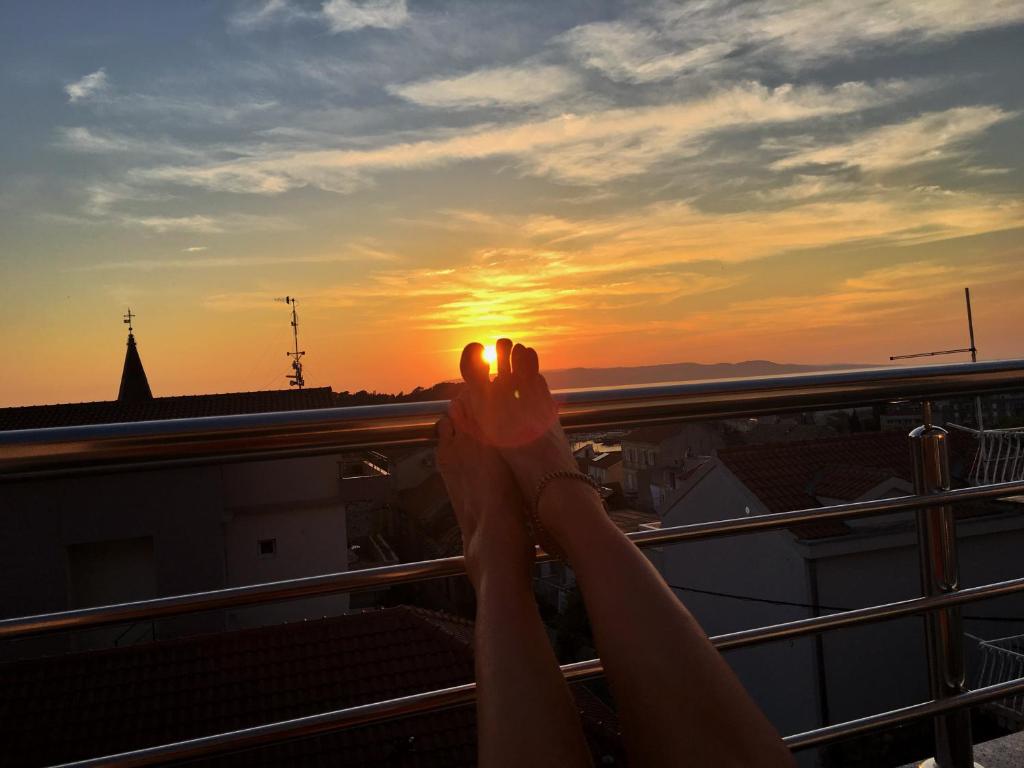 a person with their feet up on a balcony watching the sunset at Apartment and room Hoselito in Makarska