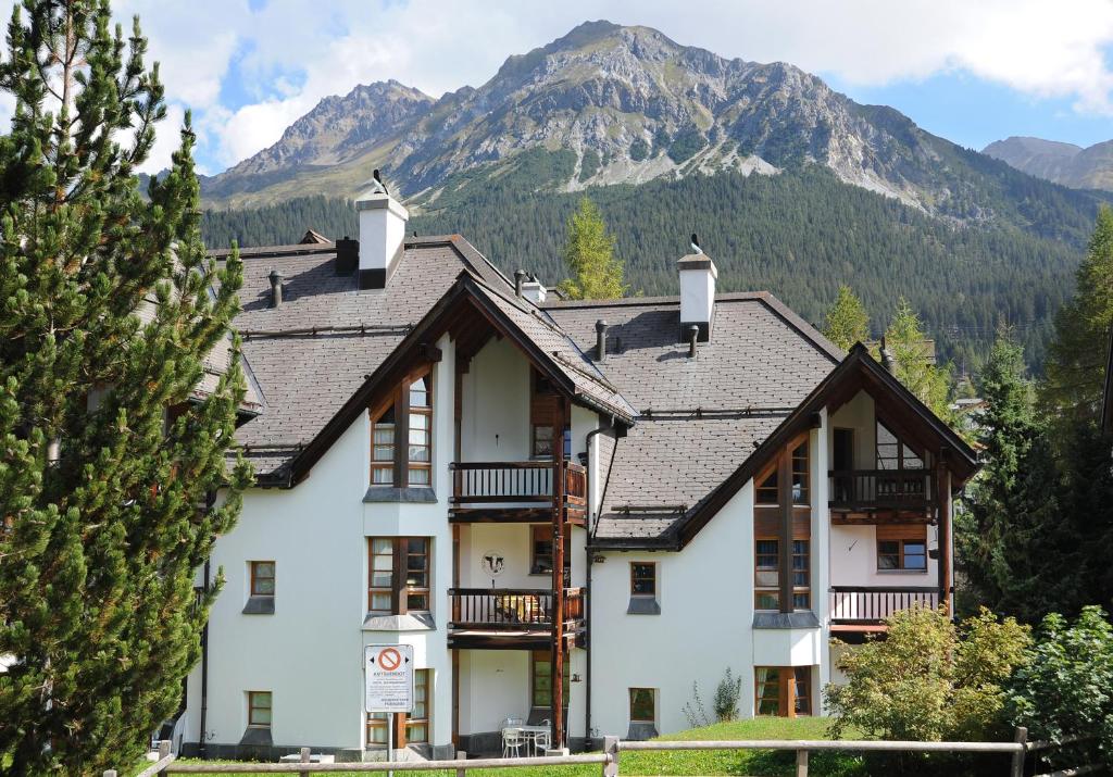 ein großes weißes Haus mit Bergen im Hintergrund in der Unterkunft Schweizerhof Drescher in Lenzerheide