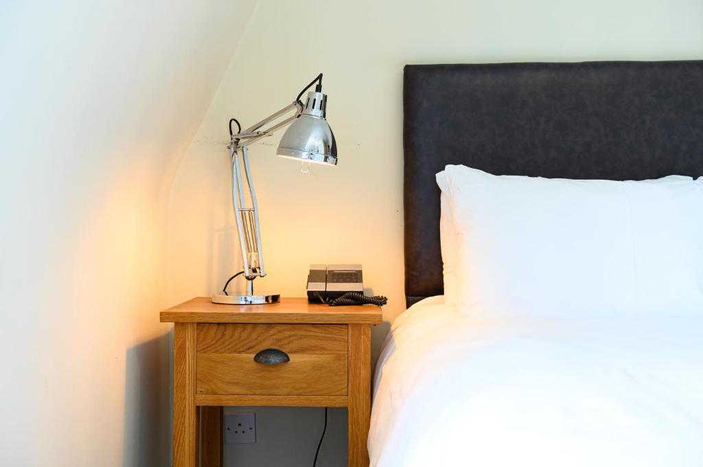 a bedroom with a bed and a lamp on a night stand at Kew Gardens Hotel in Kew