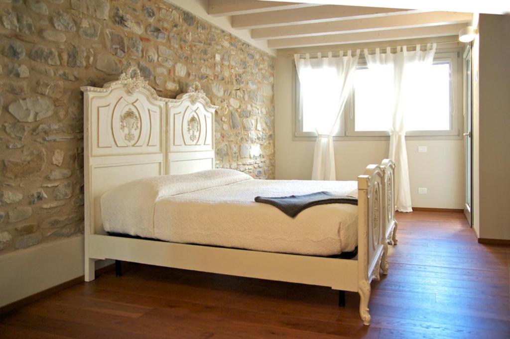 a bedroom with a white bed and a stone wall at Affittacamere Mauro e Sylvie in Bobbio