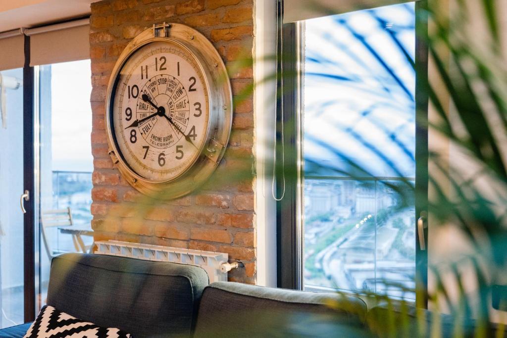 a clock on the side of a brick wall at Rooftop Apt with Large Harbor View Terrace in Constanţa