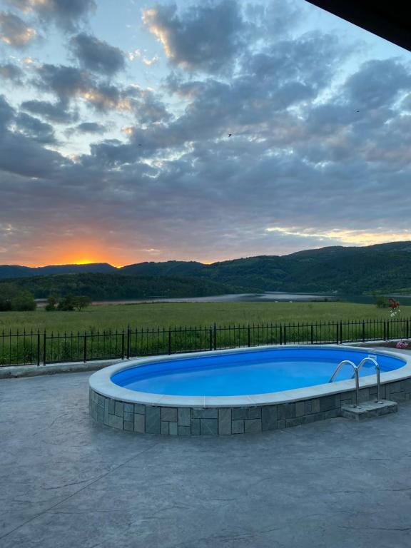 a large swimming pool with a sunset in the background at Къща за гости "Боеви" in Yakovtsi