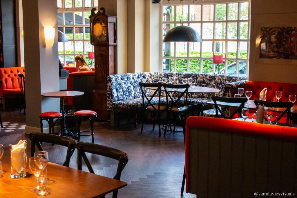 a restaurant with tables and chairs in a room with windows at The Broadway Hotel in Letchworth