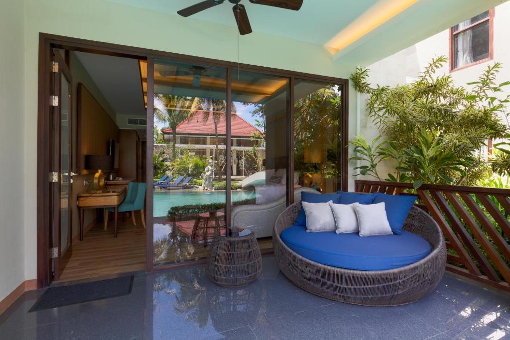 a patio with a blue couch on a balcony at The Gantari Ubud Hotel & Villa in Ubud