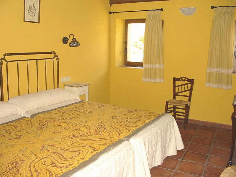 a bedroom with a bed and a chair and a window at Casa Rural Corvina in Acebo