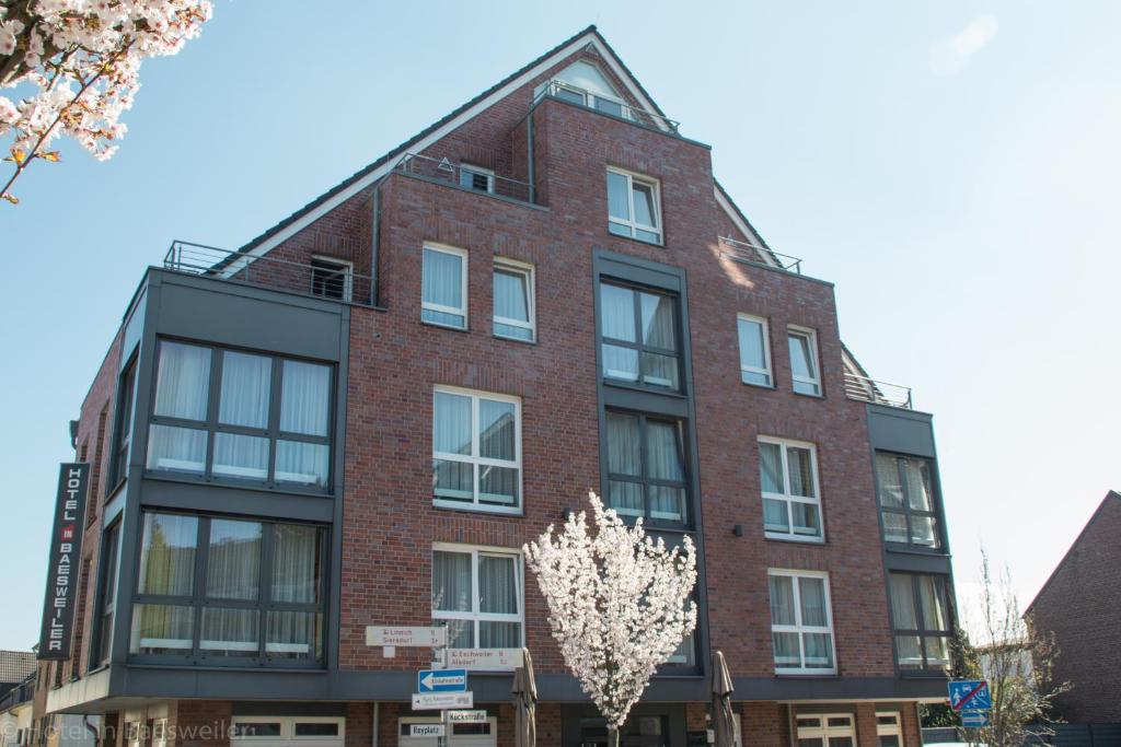 un edificio di mattoni rossi con un albero di fronte di HIB Hotel in Baesweiler a Baesweiler