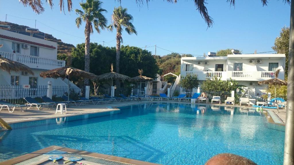 a large swimming pool in a resort with palm trees at Angelina Studios in Kardamaina