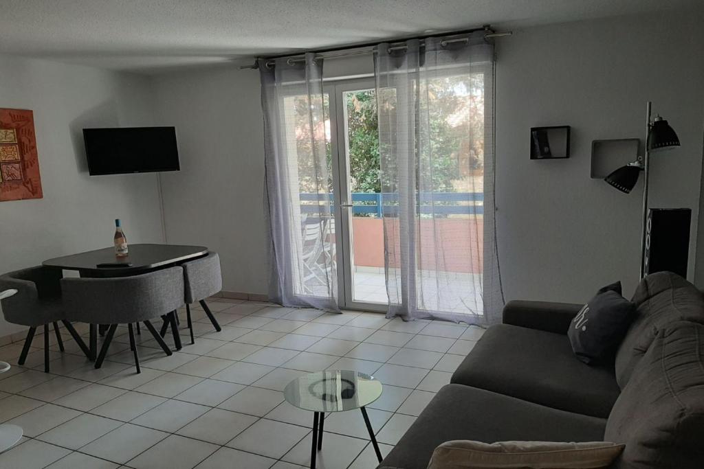 un salon avec un canapé et une table dans l'établissement T2 avec une agréable vue jardin Emeraude 35, à Canet