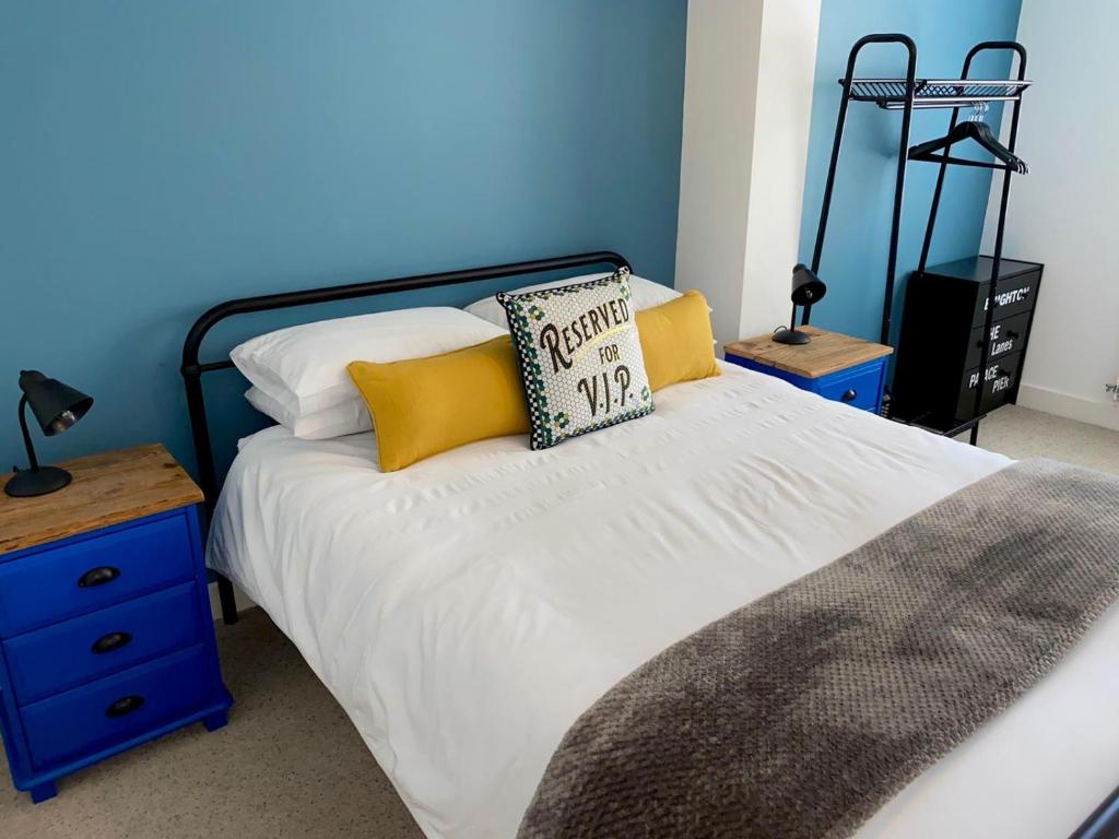 a bed with yellow and white pillows and a blue wall at Kemp Town Sea View Balcony Apartment in Brighton & Hove