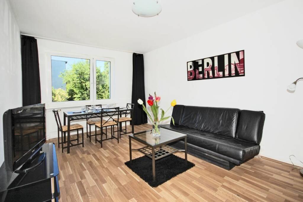 a living room with a black leather couch and a table at Apartment East Side in Berlin