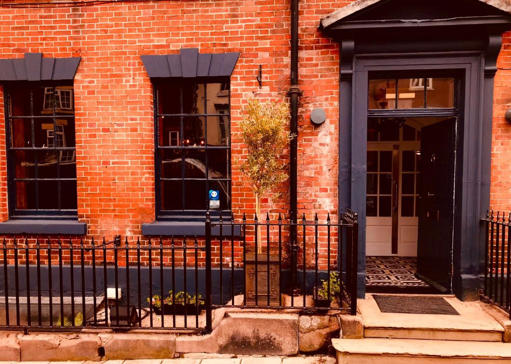 a brick building with a black fence and a door at The Silk House in Leek