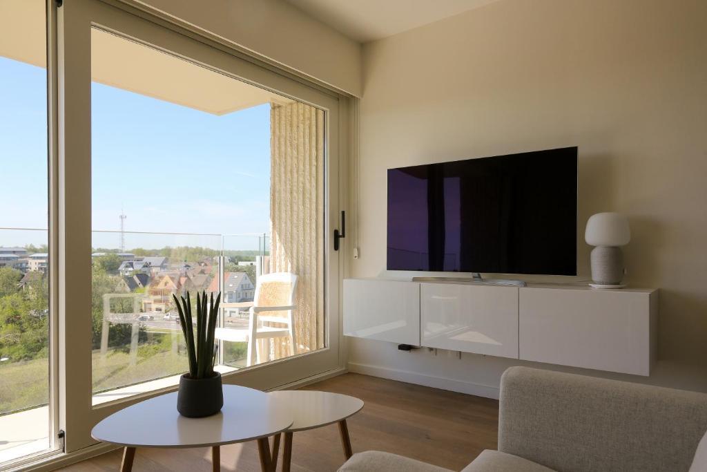 een woonkamer met een tv en een groot raam bij Vakantie-appartement Berg & Zee in Nieuwpoort