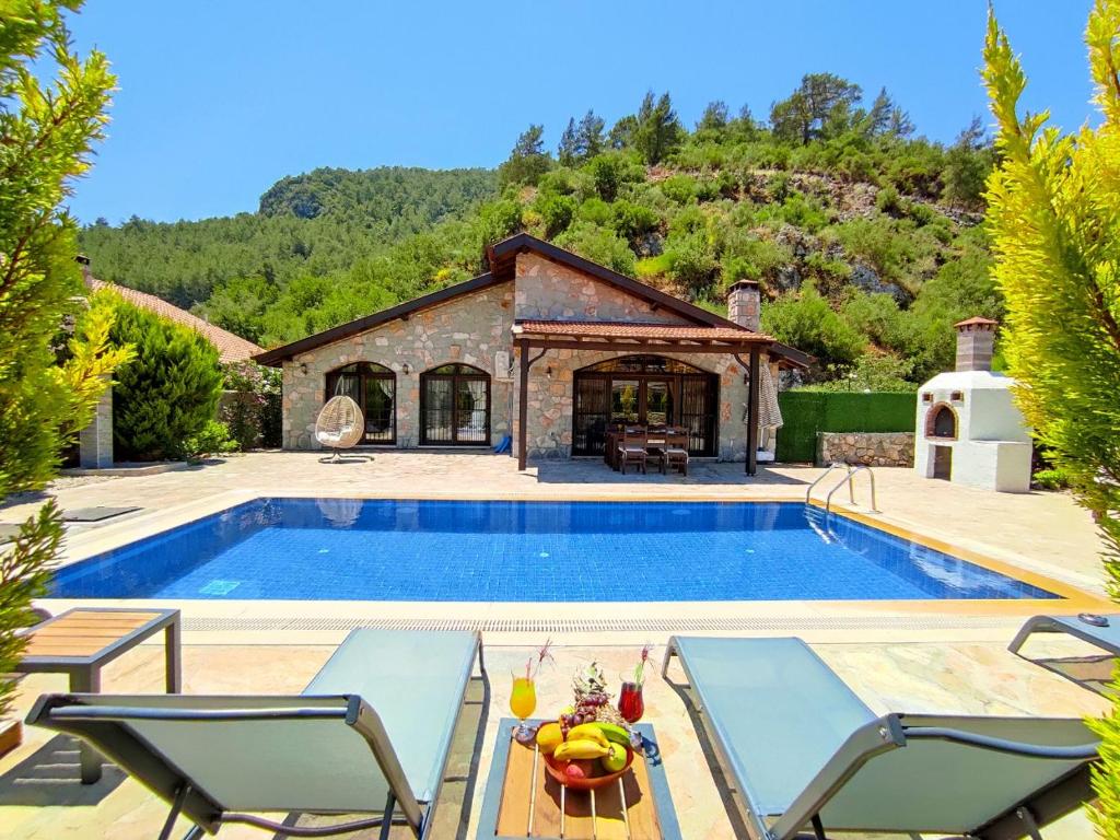 - une piscine avec des chaises et une maison dans l'établissement Villa Kayakoy 1 - Private Stone Villa, à Fethiye