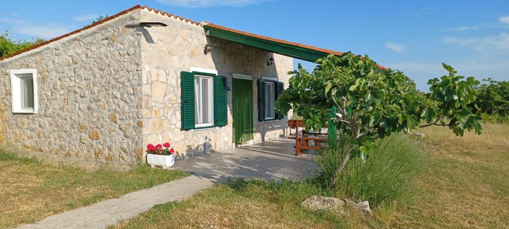a small stone house with green shutters and a tree at Krcina Holiday Home in Cres