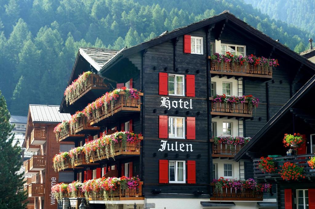 un edificio negro con cajas de flores en las ventanas en Tradition Julen Hotel, en Zermatt