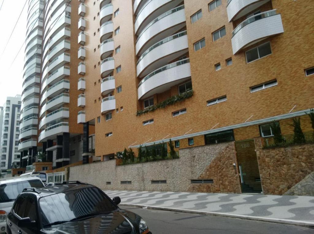 une voiture noire garée devant un grand bâtiment dans l'établissement Praia Grande canto do forte, à Praia Grande