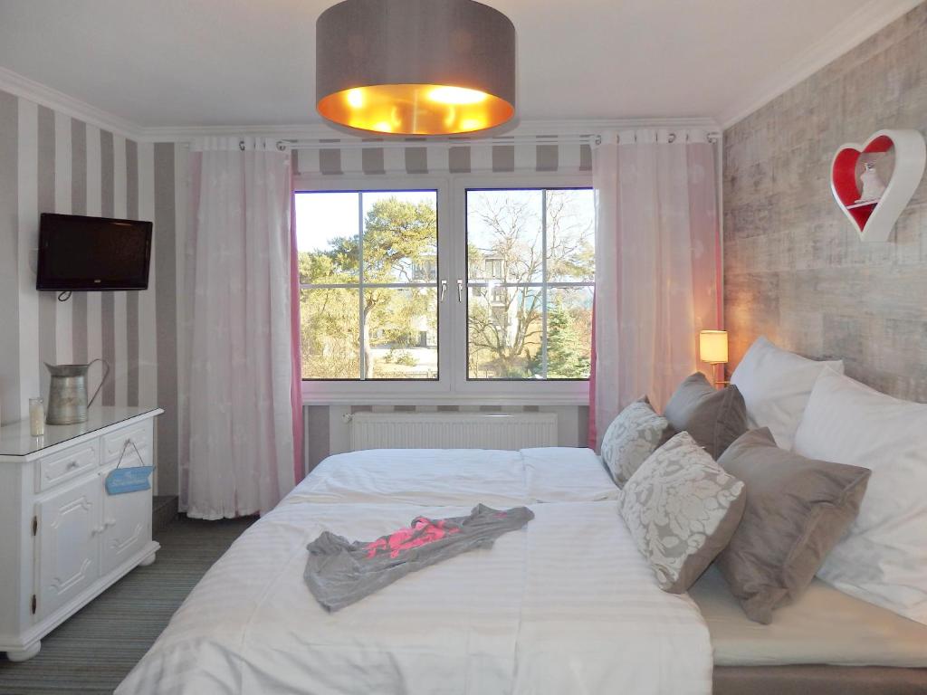 Schlafzimmer mit einem großen weißen Bett und einem Fenster in der Unterkunft Strandhotel Villa Louisa & Appartementhäuser Villa Josephine und Villa Christine in Juliusruh