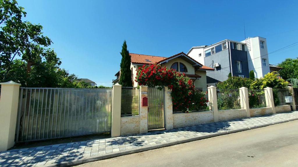 a fence in front of a house with red flowers at Vila Granada in Eforie Nord