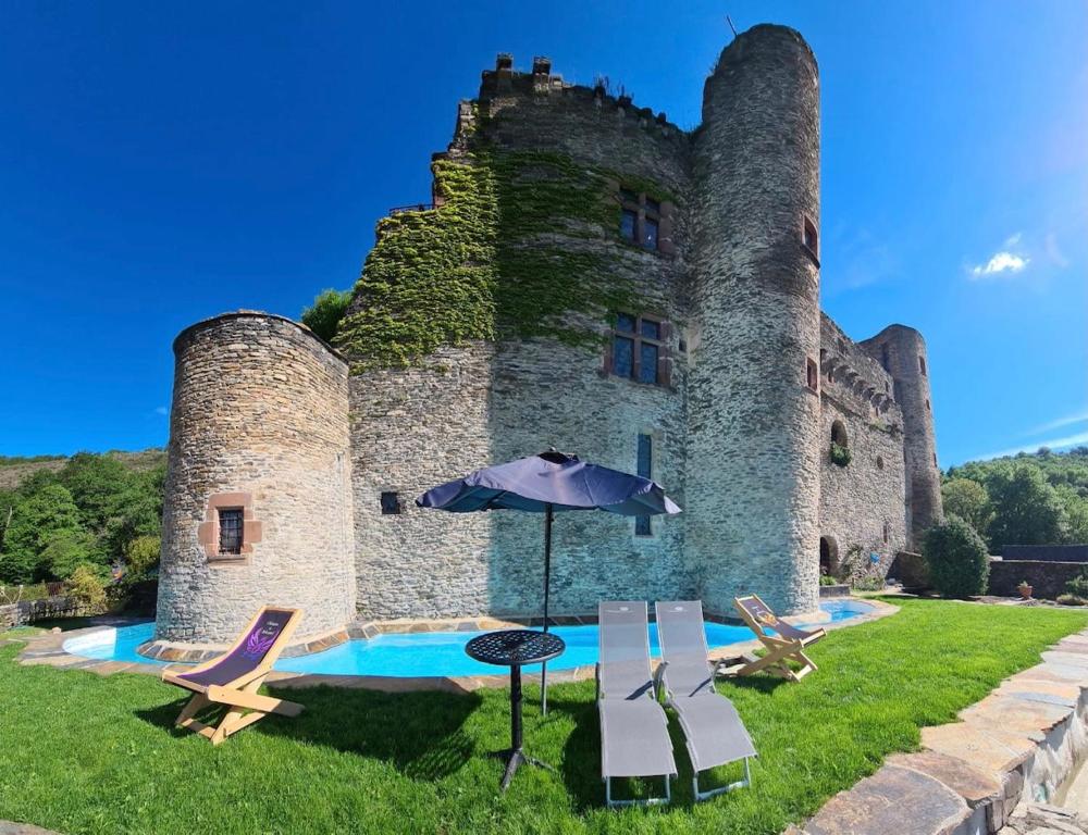 un castillo con piscina, sillas y sombrilla en Chambre d'Hôtes au Château de Belcastel en Belcastel