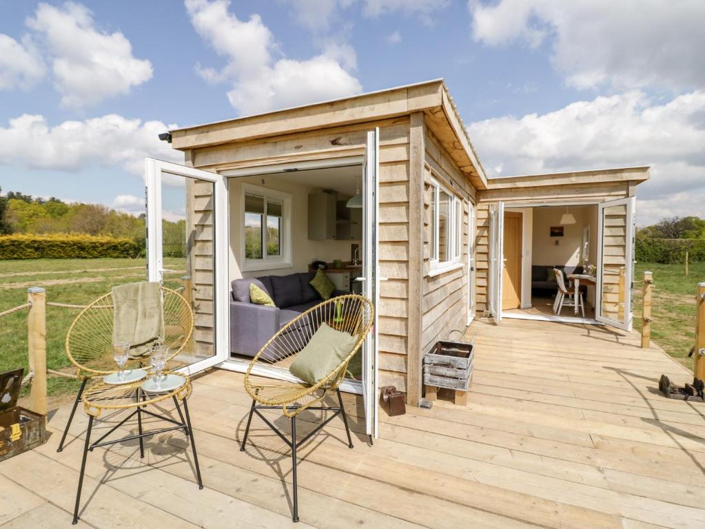 a tiny house with a porch and chairs on a deck at Malvern View Lodge in Worcester