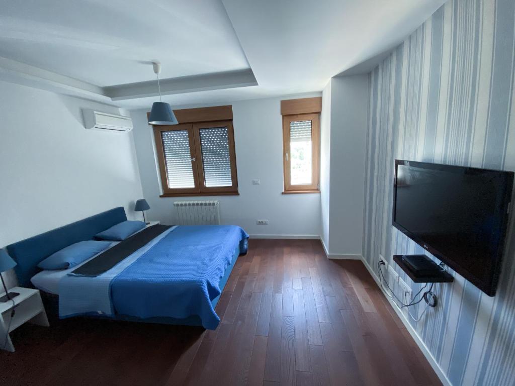 a bedroom with a blue bed and a flat screen tv at Apartment Azzurro lux in Novi Beograd