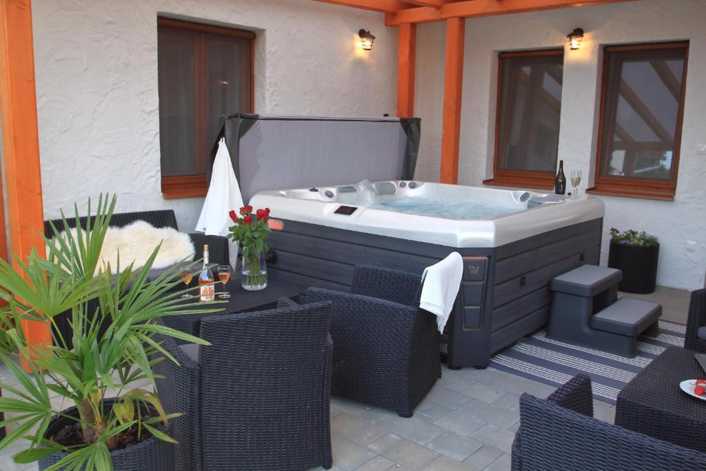 a hot tub on a patio with wicker chairs at A tornácos panzió in Kéthely