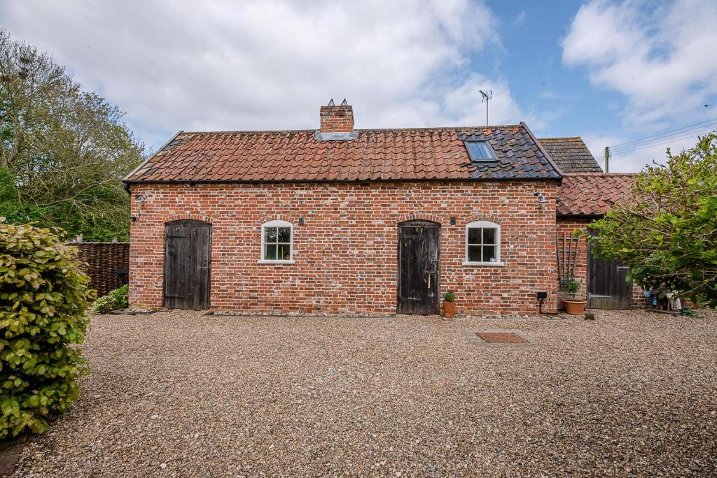 a brick house with two doors on a gravel driveway at The Wash House Middleton Air Manage Suffolk in Saxmundham