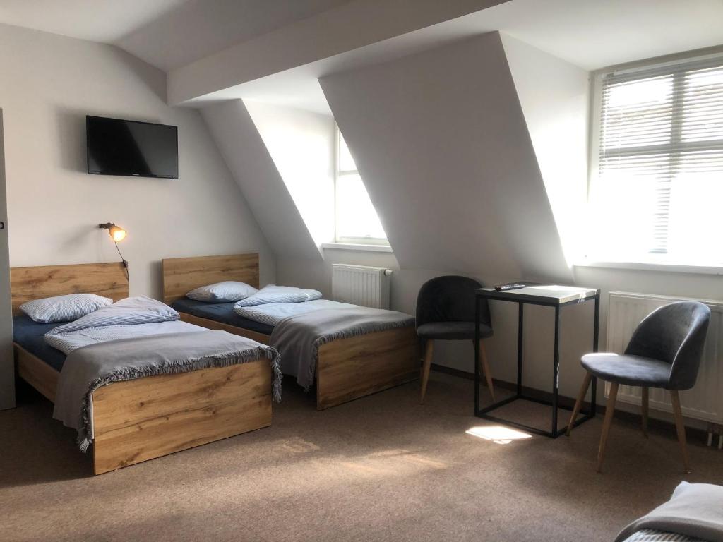 a room with two beds and a tv and two chairs at Bemma Apart Hostel in Wrocław