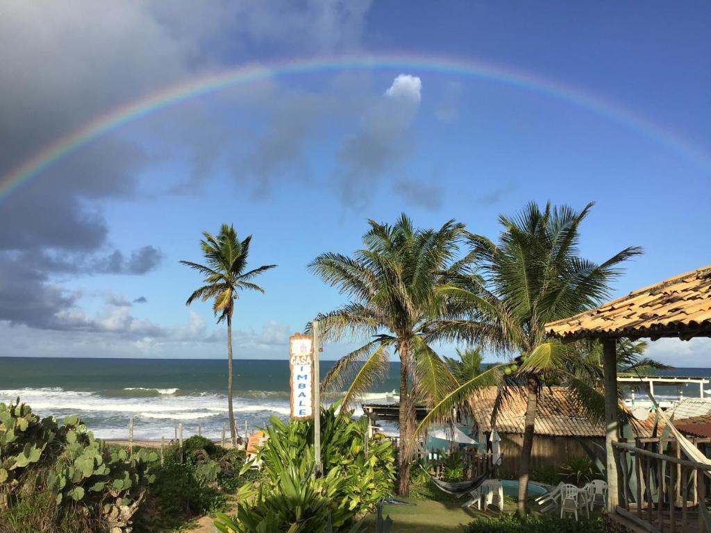 a rainbow over a beach with palm trees and the ocean at Casa ImBale in Imbassai