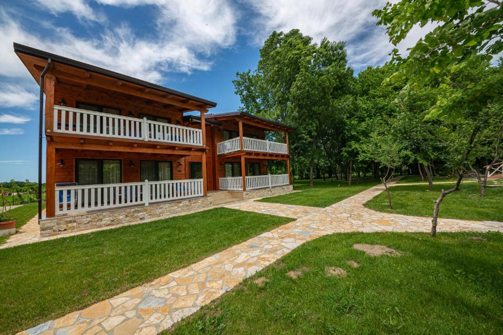 a large wooden house with a green yard at Sebastiano Resort in Lezhë