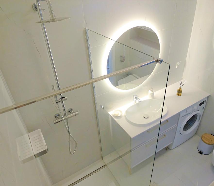 a bathroom with a shower and a sink and a mirror at Niechorze Amber Sunset apartment in Niechorze