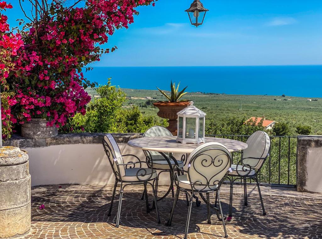einen Tisch und Stühle auf einer Terrasse mit Blumen in der Unterkunft Villa Basso 2 in Monte SantʼAngelo