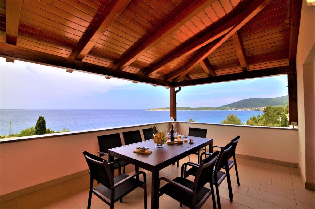 a table and chairs on a balcony with a view of the ocean at Villa Sofia in Martinšćica