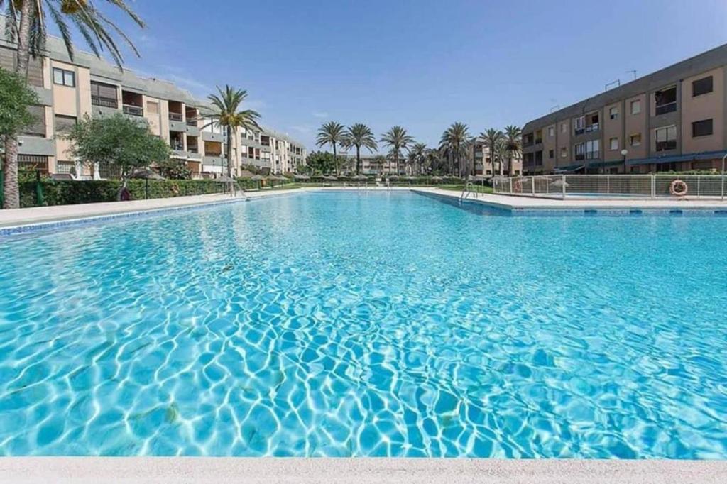 una gran piscina azul con palmeras y edificios en Expoholidays - Cabo de Gata Retamar family, en Retamar