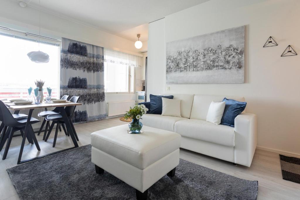 ein Wohnzimmer mit einer weißen Couch und einem Tisch in der Unterkunft Vasko luxurious suites, Rakka in Rovaniemi