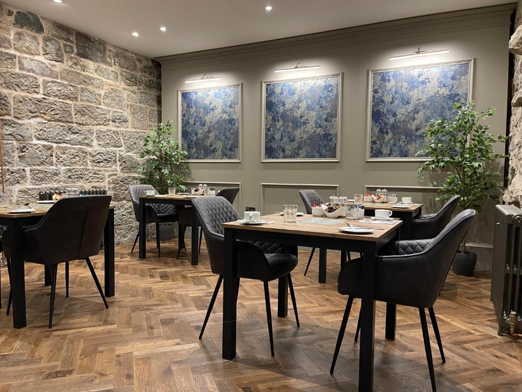 uma sala de jantar com mesas, cadeiras e janelas em Ben Cruachan Guest House em Edimburgo