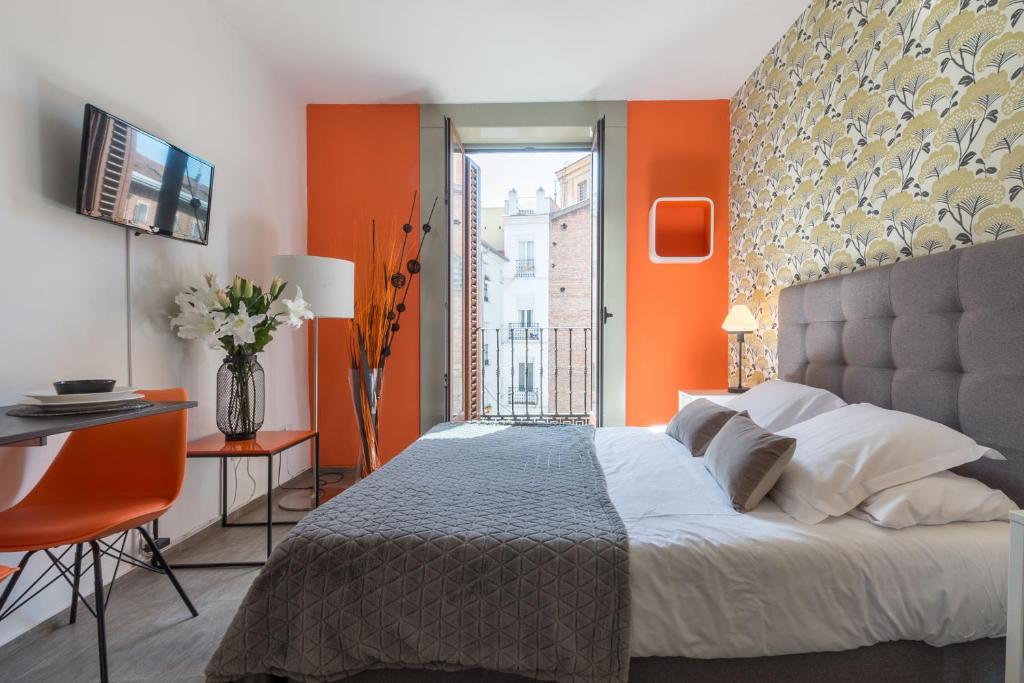 1 dormitorio con paredes de color naranja, 1 cama y 1 mesa en MIT House Santa Ana Boutique en Madrid, en Madrid