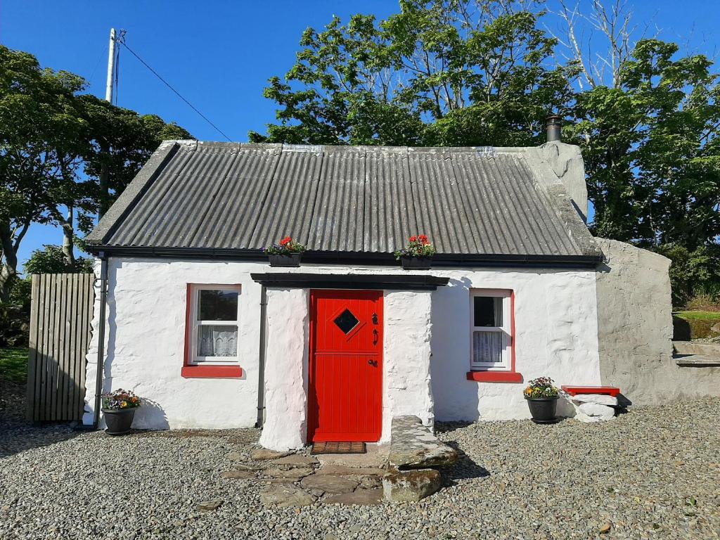 uma pequena casa branca com uma porta vermelha em Cherry Tree Cottage - Cosy 19th Century Cottage em Claragh