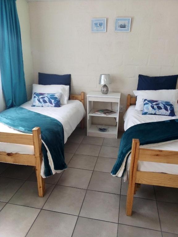 two beds in a room with blue curtains and a table at Venolla's in The Crags