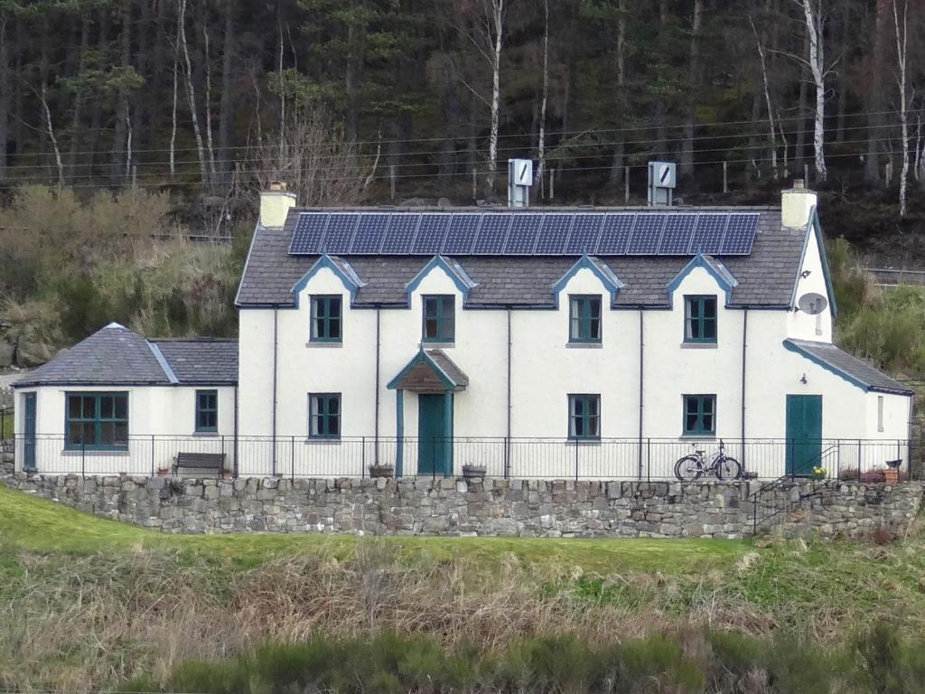 a white house with solar panels on it at The Cottage Bogroy in Carrbridge