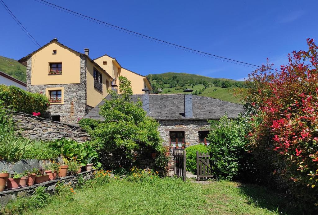 uma antiga casa de pedra numa aldeia com flores em Casa Colason em El Otero