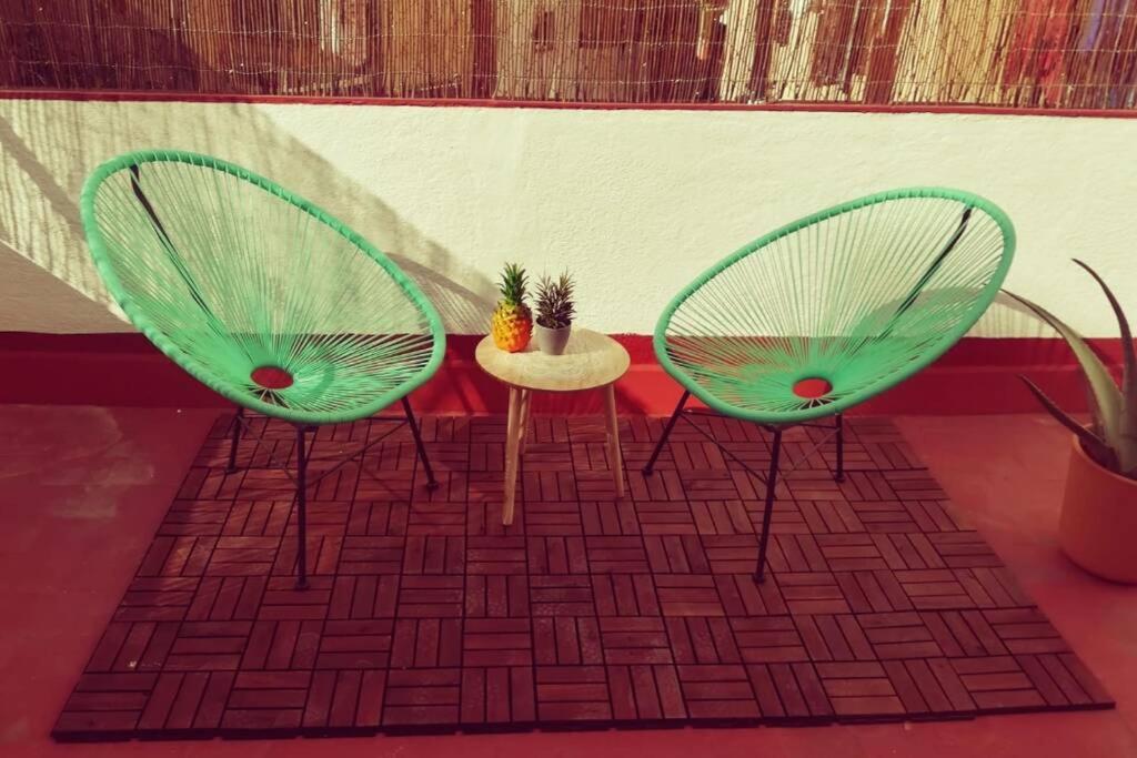 Dos sillas verdes y una mesa con una planta. en M1 Cool Loft 1 min walk to metro 15 min center by metro, en Esplugues de Llobregat