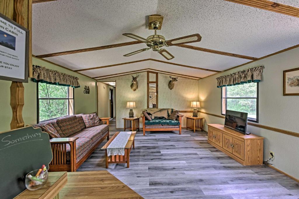 a living room with a couch and a ceiling fan at Secluded Woodsy Cabin Hike, Fish, Hunt and ATV! in Arkdale