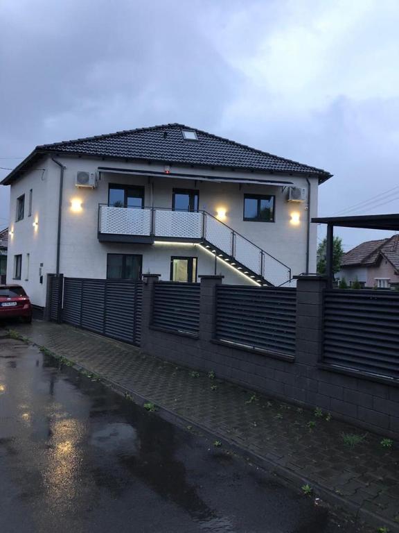 a white house with a fence in front of it at Vila El Passo in Târgu-Mureş