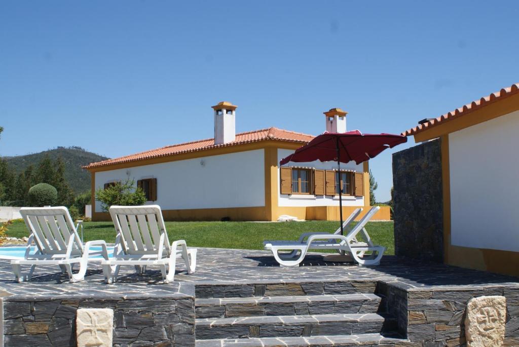 a group of white chairs and an umbrella on a patio at Casa da Eira em Dornes - Casa de campo familiar com piscina in Dornes
