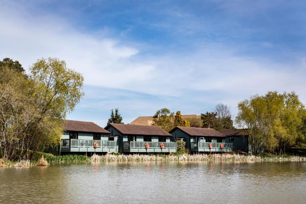 The Vale Golf & Country Club في Bishampton: صف من البيوت بجانب تجمع للمياه