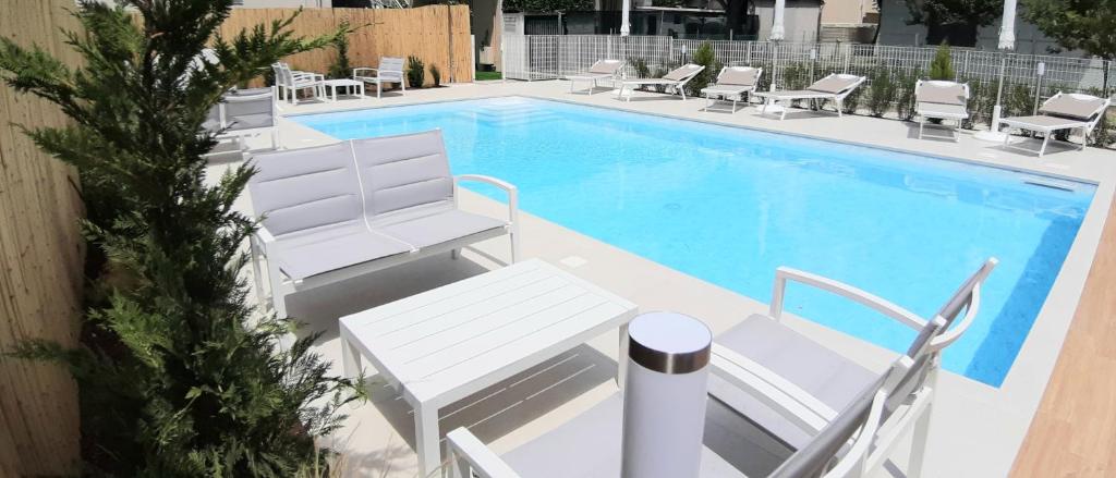 uma piscina com espreguiçadeiras brancas e um visor de piscina branca em Hotel Ermeti B&B Brunch em Riccione