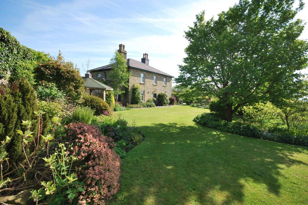 une grande maison avec une cour verdoyante plantée d'arbres et de buissons dans l'établissement Dannah Farm Country House, à Shottle